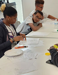 Youth sitting at white table completing activities