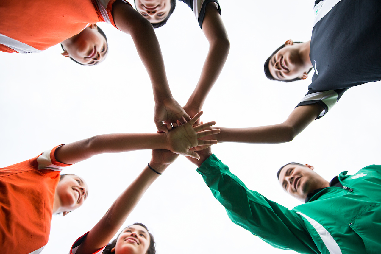 family gathering in a circle huddle and placing their hands in the middle.